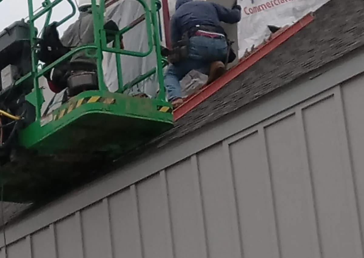 Worker on a boom lift fitting siding over house wrap